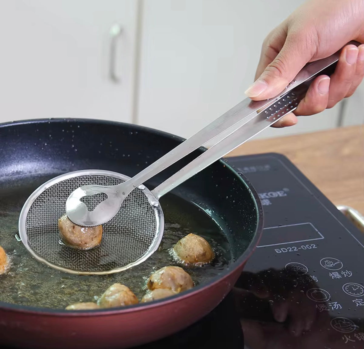 Frying strainer tongs lifting fried food and draining excess oil