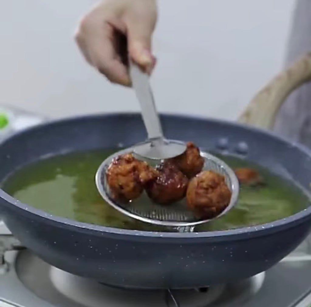 Kitchen frying strainer tongs scooping fried food from hot oil